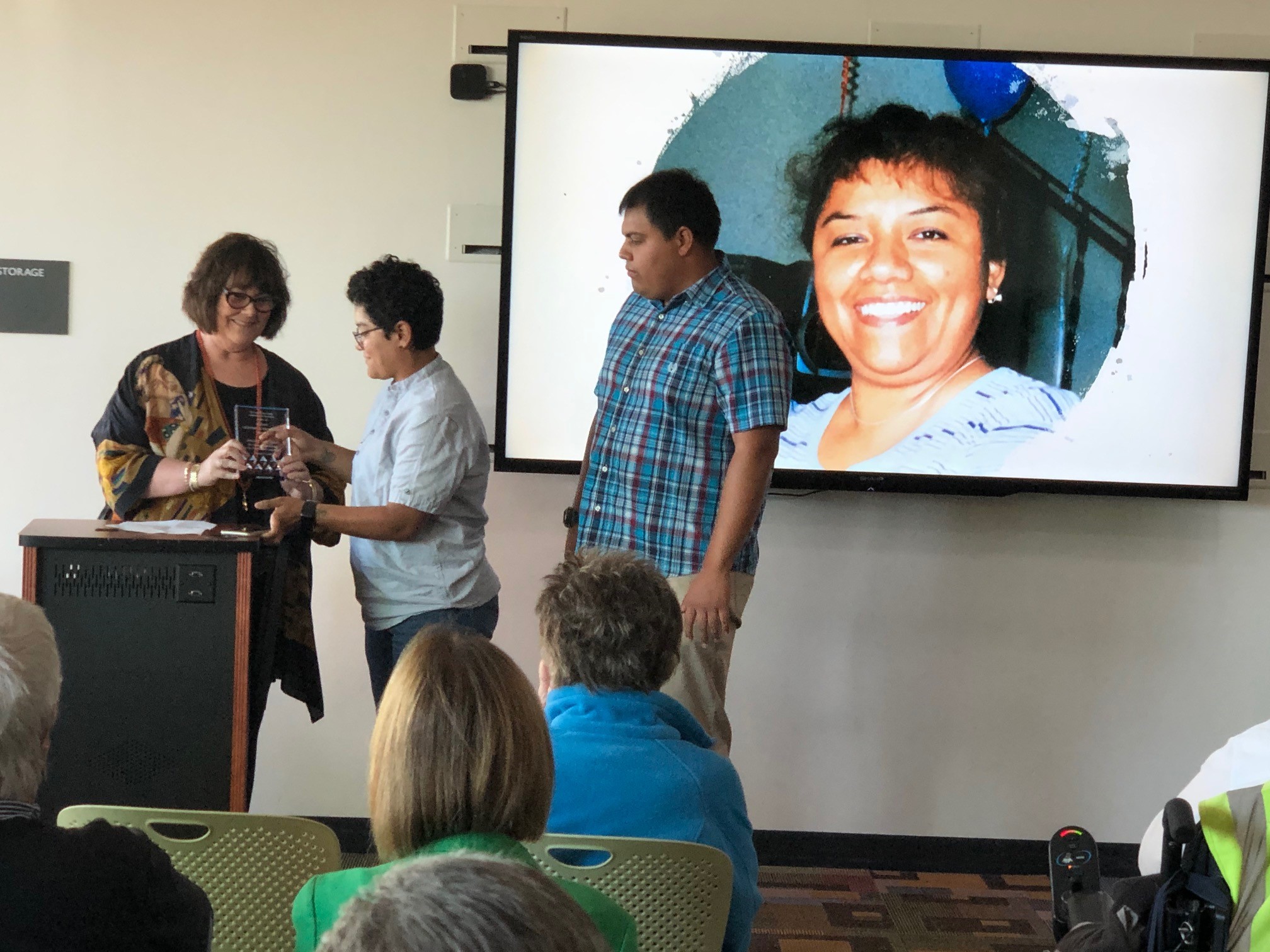 Commissioner Janet Crosse presents a Kudos Lifetime Achievement Award Angelica Victoria, accepted by her children Lily and Mitchell